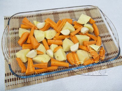 в форму укладываем нарезанные крупными кусочками морковь с картофелем и раскладываем целые зубчики чеснока